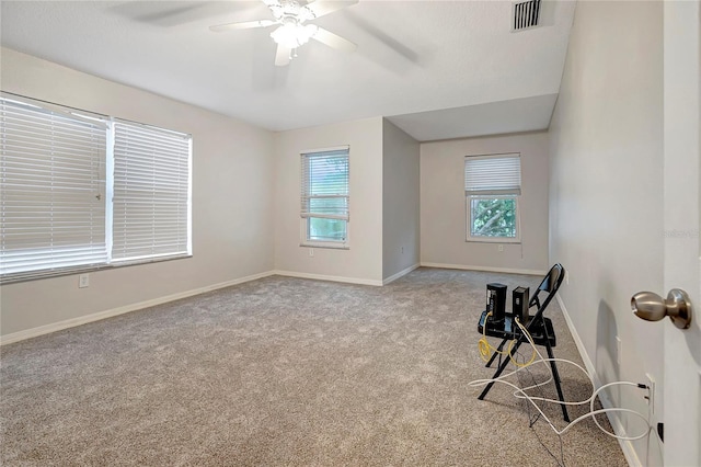 spare room featuring a ceiling fan, plenty of natural light, carpet flooring, and baseboards