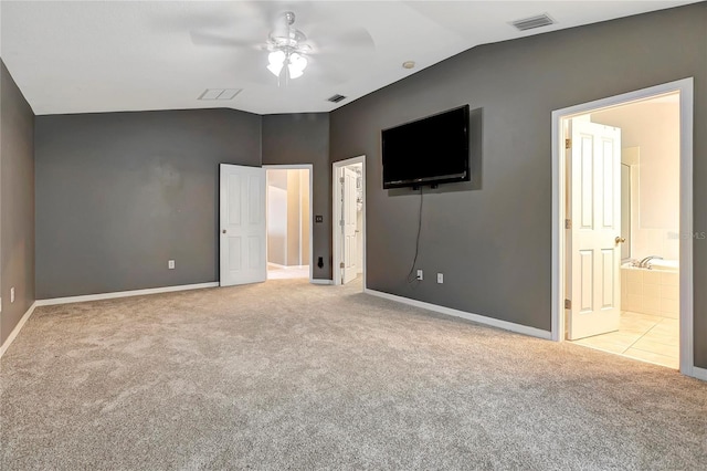 unfurnished bedroom with lofted ceiling, carpet floors, baseboards, ensuite bath, and a ceiling fan