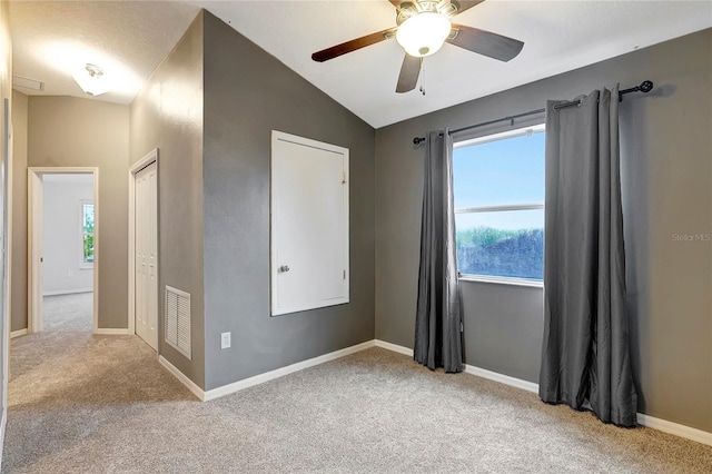 carpeted empty room featuring vaulted ceiling, a ceiling fan, and baseboards
