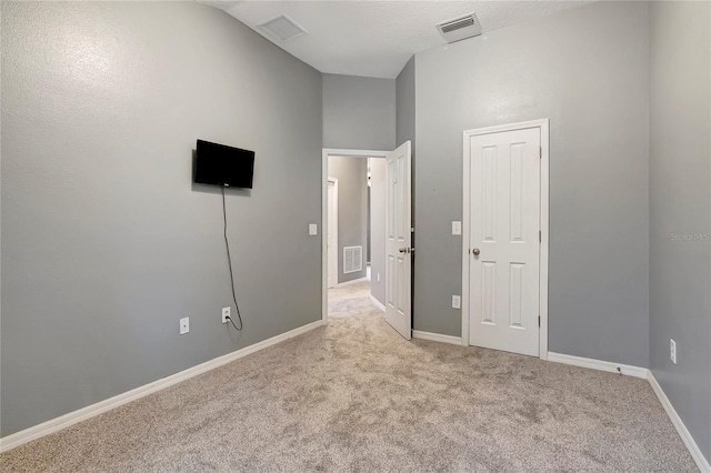 unfurnished bedroom featuring light colored carpet, baseboards, and vaulted ceiling