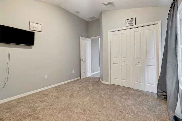 unfurnished bedroom featuring carpet flooring, lofted ceiling, a closet, and baseboards