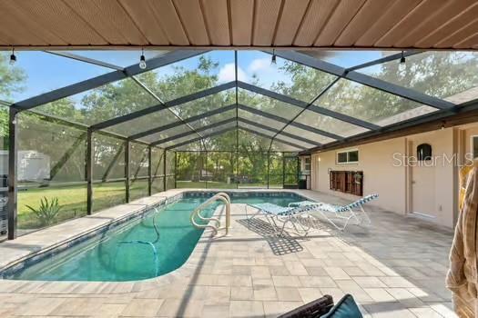 5216 Hope Ln, Spring Hill, FL 34606 - outdoor pool with a patio area and glass enclosure