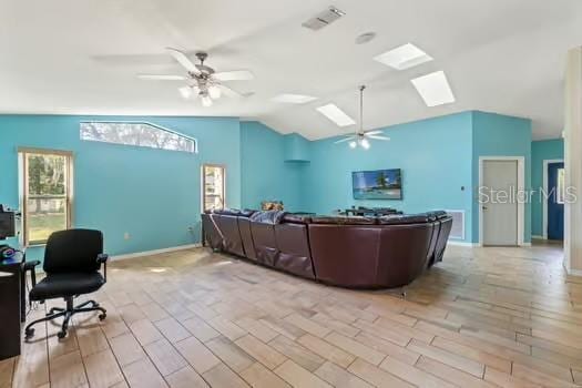 5216 Hope Ln, Spring Hill, FL 34606 - living room with a ceiling fan, vaulted ceiling, a skylight, light wood-style flooring, and baseboards