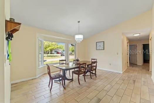 5216 Hope Ln, Spring Hill, FL 34606 - dining space featuring baseboards, light wood finished floors, a chandelier, and vaulted ceiling