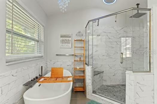 5216 Hope Ln, Spring Hill, FL 34606 - bathroom with tile walls, a freestanding bath, a marble finish shower, and a wainscoted wall