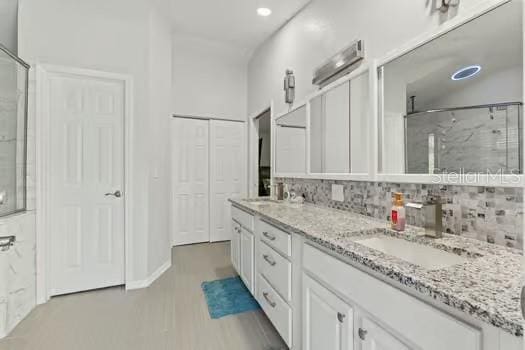 5216 Hope Ln, Spring Hill, FL 34606 - full bathroom with decorative backsplash, double vanity, a stall shower, recessed lighting, and wood finished floors