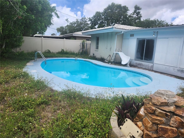 view of pool with a water slide and fence