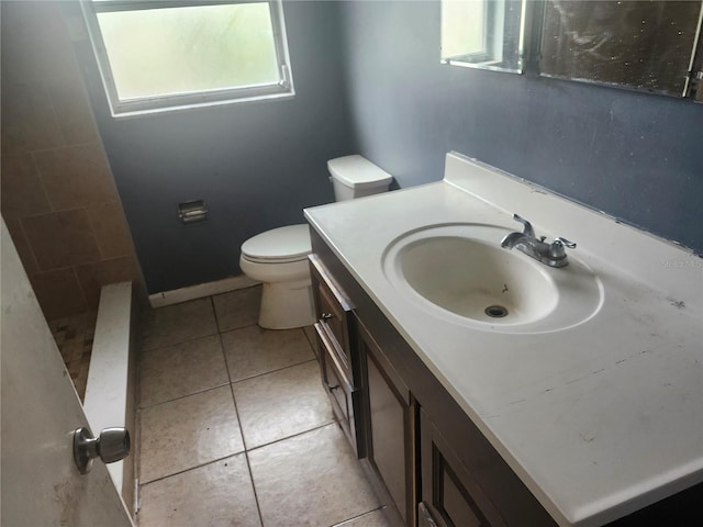 full bath featuring toilet, vanity, tile patterned flooring, a tile shower, and baseboards