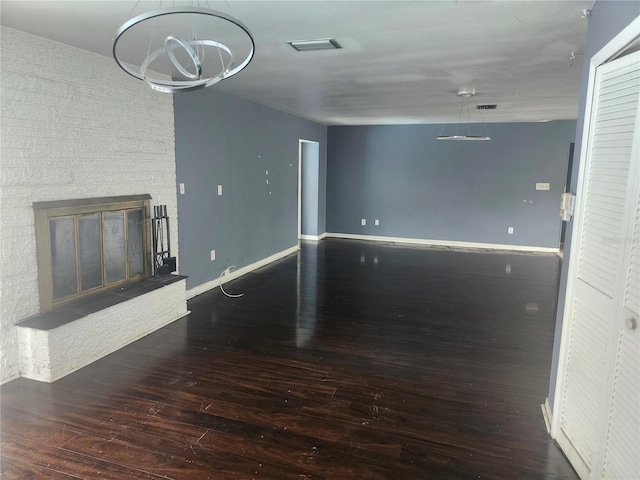 unfurnished living room featuring hardwood / wood-style floors, a chandelier, baseboards, and a glass covered fireplace