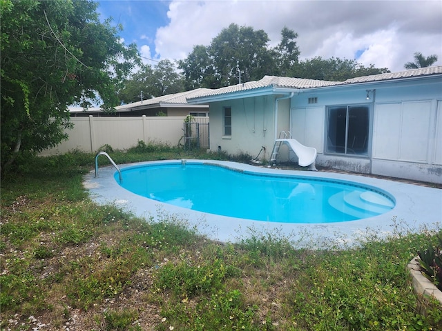 view of swimming pool featuring a water slide and fence