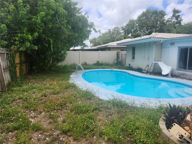 view of swimming pool with a water slide and a fenced backyard