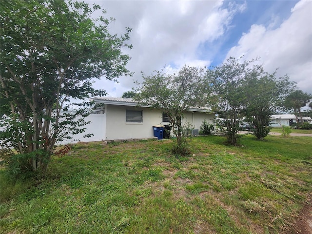 rear view of house featuring stucco siding, a yard, and central air condition unit