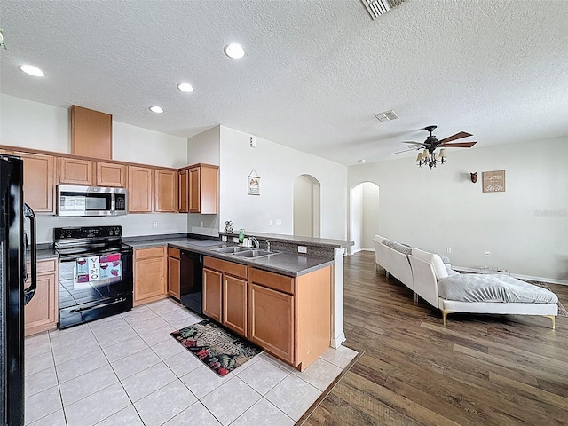 kitchen featuring black appliances, open floor plan, arched walkways, a ceiling fan, and dark countertops