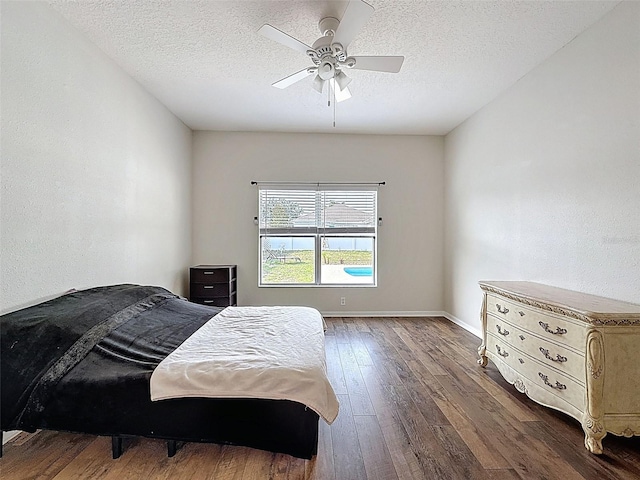 bedroom with wood-type flooring, a textured ceiling, baseboards, and a ceiling fan