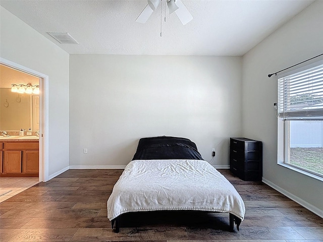 bedroom featuring wood finished floors, connected bathroom, baseboards, and a ceiling fan