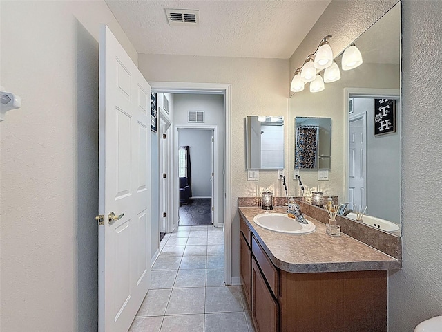bathroom featuring a textured wall, tile patterned floors, vanity, a textured ceiling, and baseboards