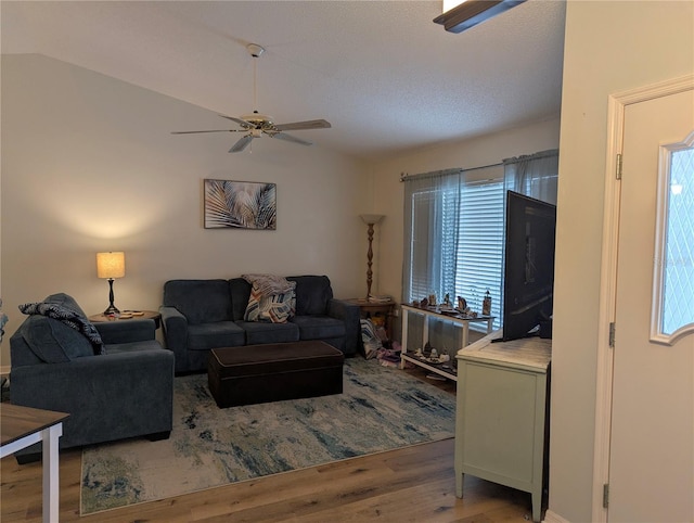 living area with wood finished floors, ceiling fan, vaulted ceiling, and plenty of natural light