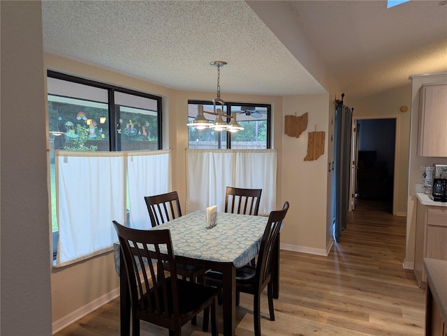 dining space featuring a chandelier, light wood-style floors, a textured ceiling, and baseboards