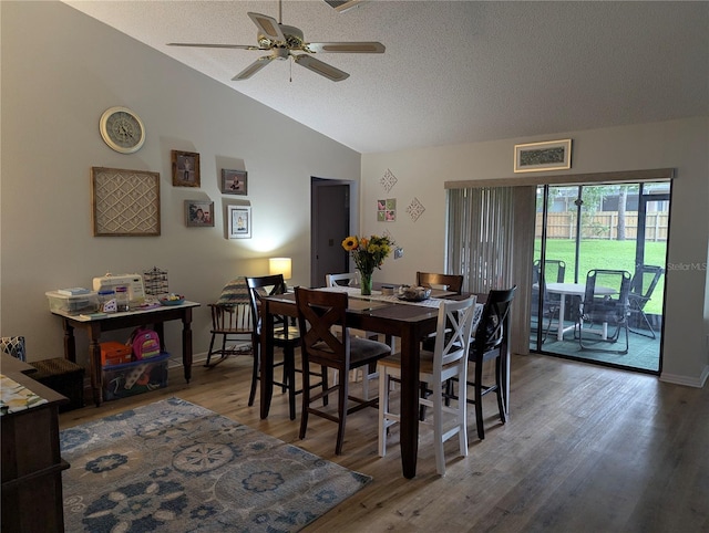 dining room with a ceiling fan, vaulted ceiling, wood finished floors, and a textured ceiling