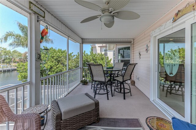 sunroom / solarium featuring a water view and a ceiling fan