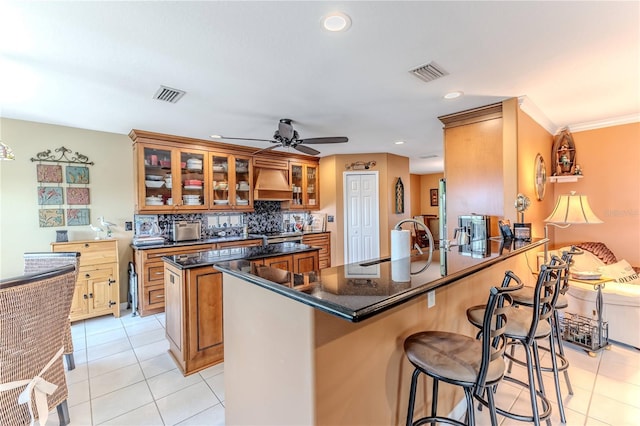 kitchen with a sink, brown cabinets, light tile patterned floors, a peninsula, and recessed lighting