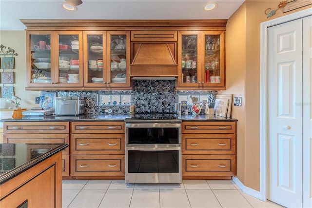bar area featuring custom exhaust hood, decorative backsplash, light tile patterned floors, and double oven range