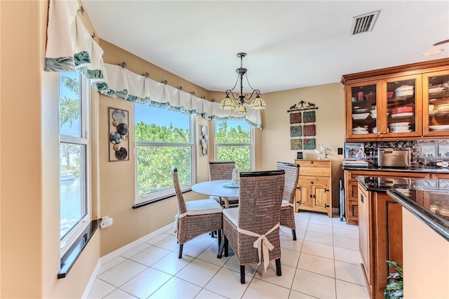 dining space featuring light tile patterned flooring, a chandelier, and baseboards