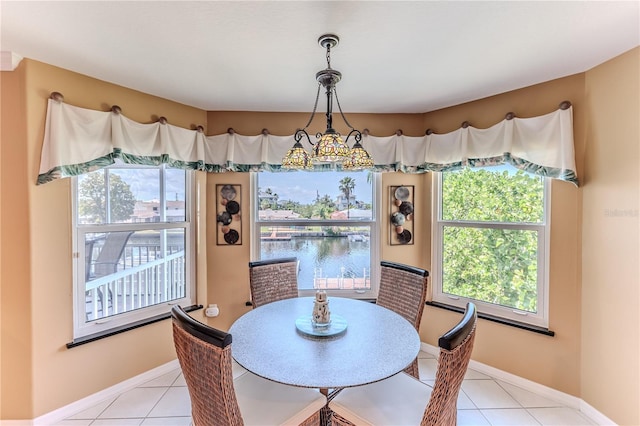 dining space featuring light tile patterned floors, a water view, and baseboards