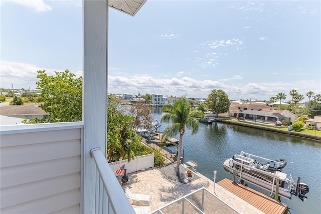 balcony with a water view, boat lift, and a dock