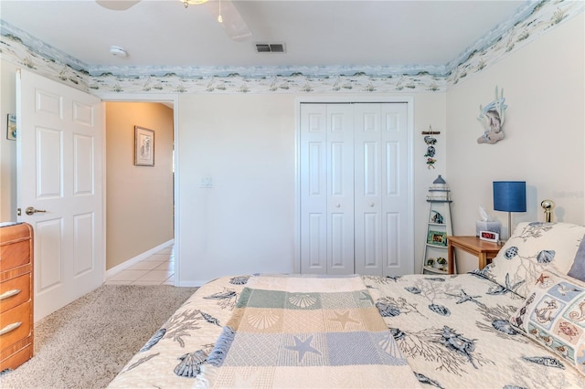 tiled bedroom with carpet, a closet, baseboards, and a ceiling fan