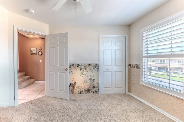 unfurnished bedroom featuring carpet flooring, a closet, and a ceiling fan