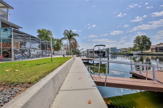 dock with a water view, a lawn, boat lift, and a lanai