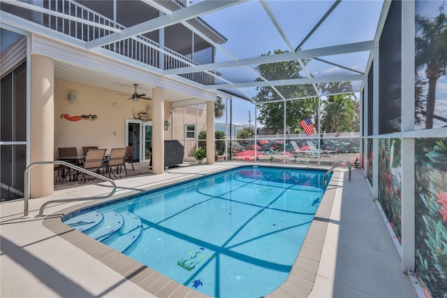 outdoor pool with a patio area, a ceiling fan, and glass enclosure