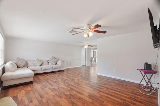 12106 Bear Creek Ln, Hudson, FL 34667 - living area featuring a ceiling fan, wood finished floors, a wainscoted wall, and a decorative wall
