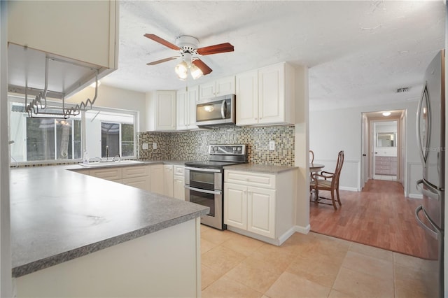 12106 Bear Creek Ln, Hudson, FL 34667 - kitchen with appliances with stainless steel finishes, tasteful backsplash, a sink, a ceiling fan, and white cabinetry