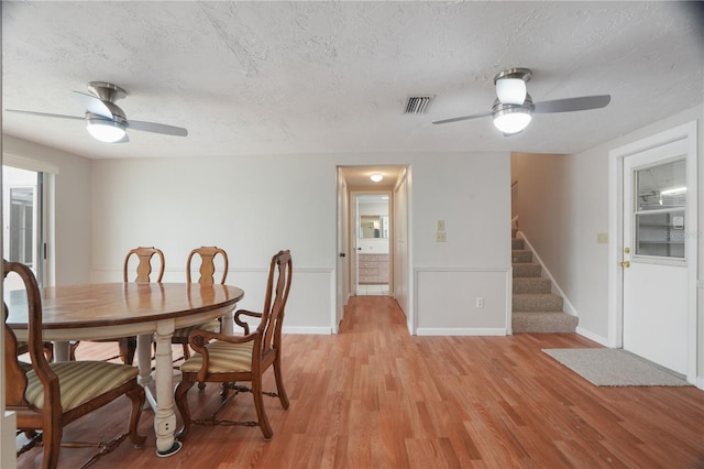 12106 Bear Creek Ln, Hudson, FL 34667 - dining space with a ceiling fan, light wood finished floors, a textured ceiling, stairway, and baseboards
