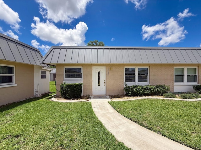 11821 Boynton Ln, New Port Richey, FL 34654 - view of front of home with brick siding, a front lawn, a standing seam roof, and metal roof