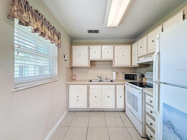 11821 Boynton Ln, New Port Richey, FL 34654 - kitchen with white appliances, a sink, under cabinet range hood, light tile patterned floors, and backsplash
