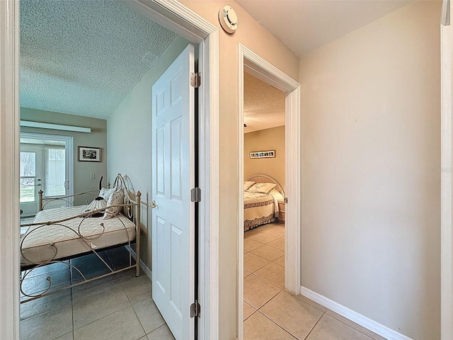11821 Boynton Ln, New Port Richey, FL 34654 - hallway featuring light tile patterned floors, a textured ceiling, and baseboards
