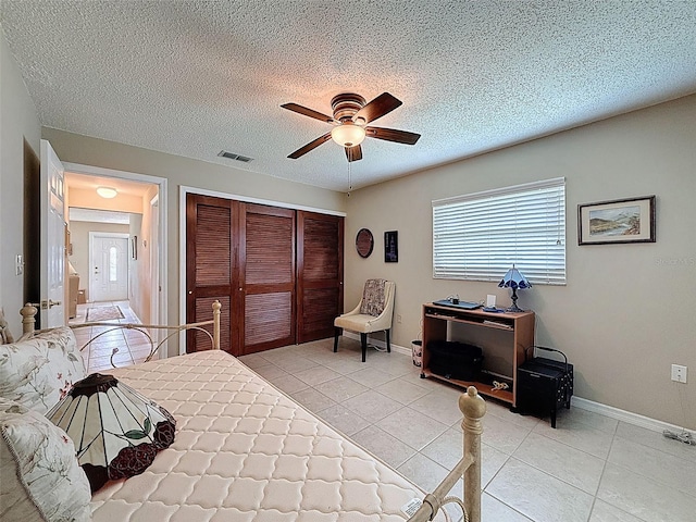11821 Boynton Ln, New Port Richey, FL 34654 - bedroom featuring a closet, light tile patterned floors, multiple windows, a ceiling fan, and a textured ceiling