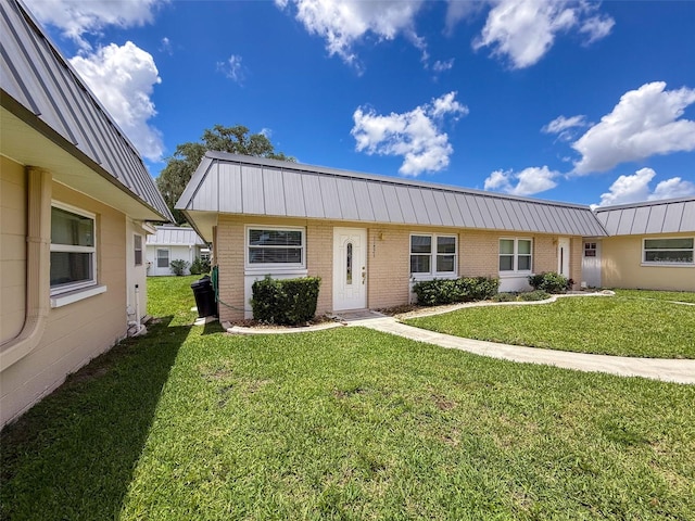 11821 Boynton Ln, New Port Richey, FL 34654 - view of front of house featuring brick siding, a front yard, and metal roof