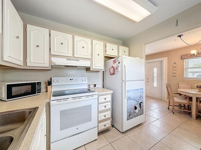 11821 Boynton Ln, New Port Richey, FL 34654 - kitchen with white appliances, under cabinet range hood, light tile patterned floors, light countertops, and white cabinetry