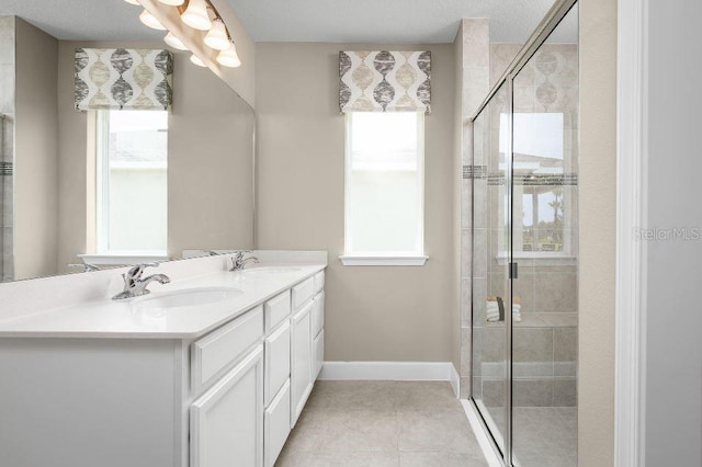 bathroom with tile patterned flooring, a stall shower, double vanity, and baseboards