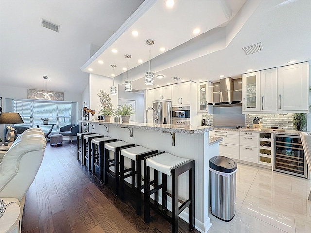 13627 Glaze Brook Dr, Hudson, FL 34667 - kitchen with wall chimney exhaust hood, beverage cooler, appliances with stainless steel finishes, a breakfast bar, and glass insert cabinets