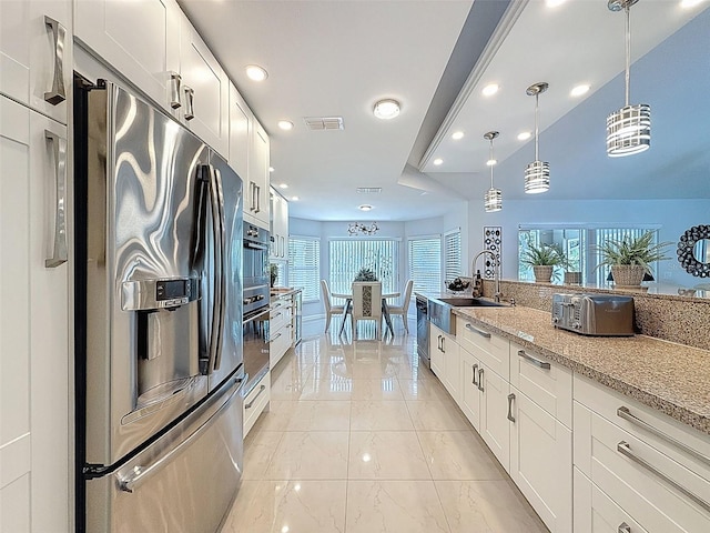 13627 Glaze Brook Dr, Hudson, FL 34667 - kitchen featuring stainless steel fridge, a sink, dishwasher, white cabinetry, and decorative light fixtures