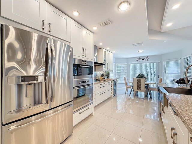 13627 Glaze Brook Dr, Hudson, FL 34667 - kitchen featuring appliances with stainless steel finishes, recessed lighting, white cabinetry, backsplash, and light stone counters