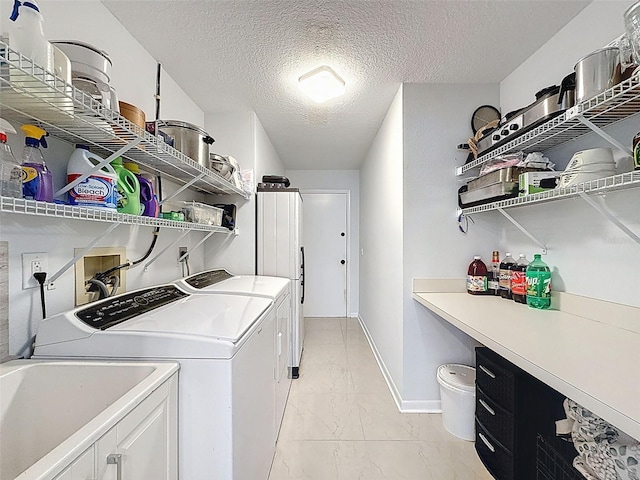 13627 Glaze Brook Dr, Hudson, FL 34667 - laundry area featuring separate washer and dryer, light marble finish flooring, a textured ceiling, baseboards, and cabinet space