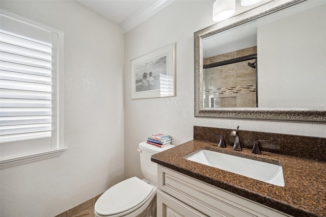 full bathroom with toilet, vanity, tiled shower, and a textured wall