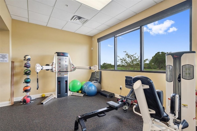 exercise area featuring baseboards and a paneled ceiling