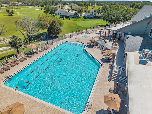 community pool with fence, a patio, and view of golf course